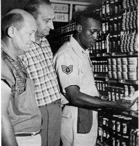 1962 at James Connally Air Force Base, Texas: Air Force Staff Sgt. William Heard, chief of merchandising at this commissary, looks at products on the shelf with two civilian employees. (Archive photo)