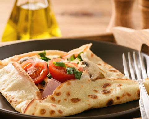 Crepe folded into a square with tomatoes cheese and ham filling