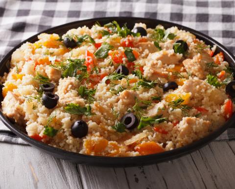 Bowl of couscous with canned tuna, olives, walnuts, and peppercinis.